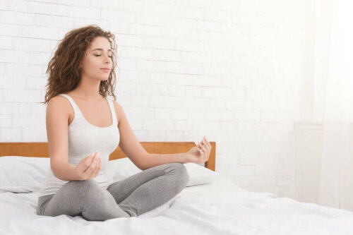 Kvinne mediterer på sengen