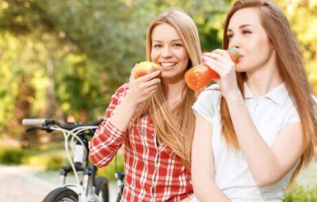 to jenter som spiser frukt og drikker juice