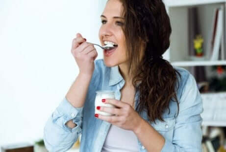 Kvinne som spiser yoghurt for å forbedre tarmfloraen