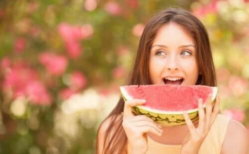 Kvinne som spiser en gigantisk vannmelonskive