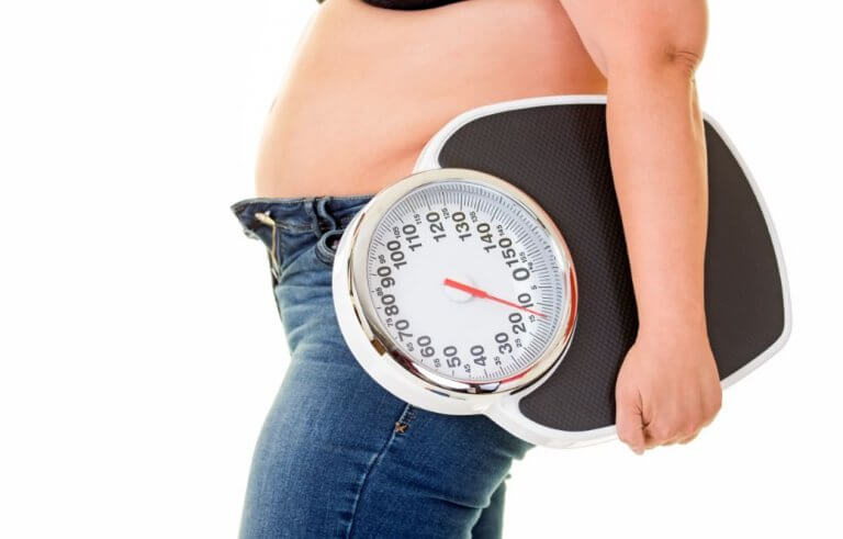 Vrouw met overgewicht houdt een weegschaal vast