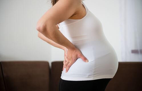zwangere vrouw met handen in de rug heeft rugpijn