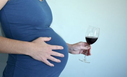 zwangere vrouw heeft een vol wijnglas in haar hand