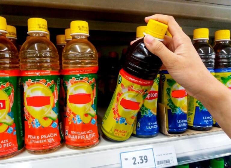Dłoń sięgająca po napój w butelce z półki sklepowej - niezdrowe jedzenie, którego należy unikać