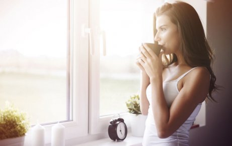 kobieta pijąca kawę w oknie i czekająca na poranny trening