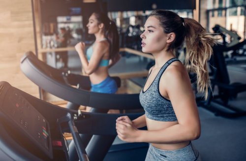 Dwie kobiety biegające na bieżniach na siłowni - jak nie narażać zdrowia podczas treningu