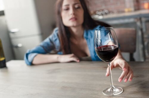 Kobieta sięgająca po kieliszek wina na stole - złe nawyki