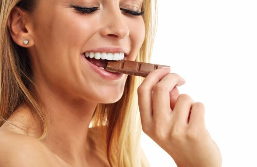 czekolada i ćwiczenia - kobieta jedząca czekoladę
