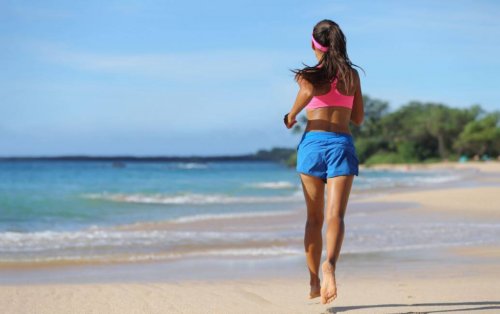 Kobieta biegnąca boso po plaży ćwiczy kardio o umiarkowanej intensywności