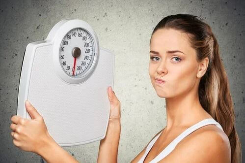 Kobieta trzymająca wagę - szczupłość a otyłość metaboliczna