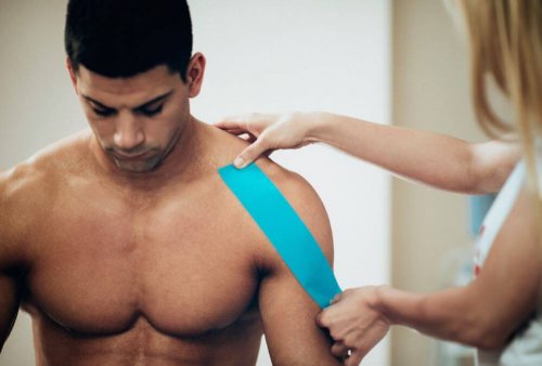 fizjoterapeutka nakłada taśmę na ramię mężczyzny