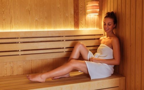 Kobieta siedząca na ławce w saunie - zalety sauny