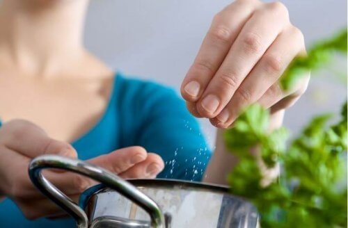 Kobieta wsypująca szczyptę soli do garnka - dzienne spożycie soli