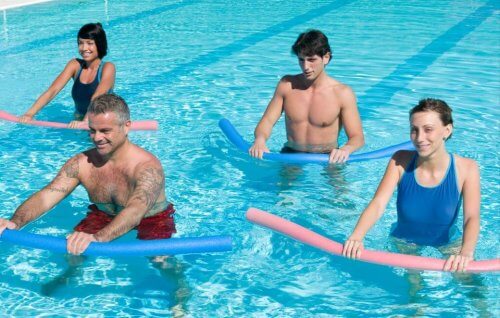 Osoby ćwiczące w basenie z makaronem