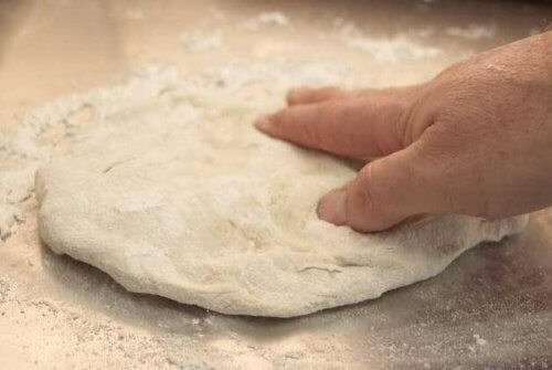 Ręka gniotąca ciasto na pizzę