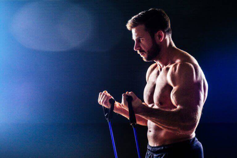 Mężczyzna ćwiczący biceps z gumami - łatwe ćwiczenia ramion