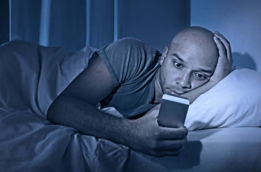 Mężczyzna w łóżku z telefonem, dlaczego nie mogę zasnąć