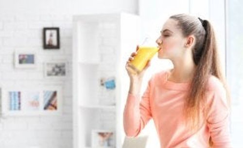 Kobieta pije sok pomarańczowy