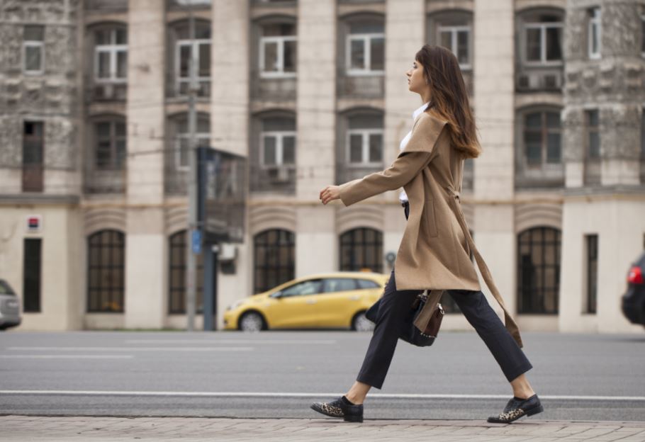 Mulher caminhando na cidade com postura flexionada