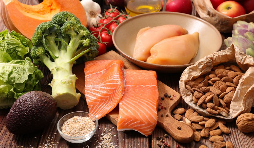 Vários alimentos saudáveis como salmão, peixe, brócolis, amêndoas, abacate, tomate, alface, abóbora...