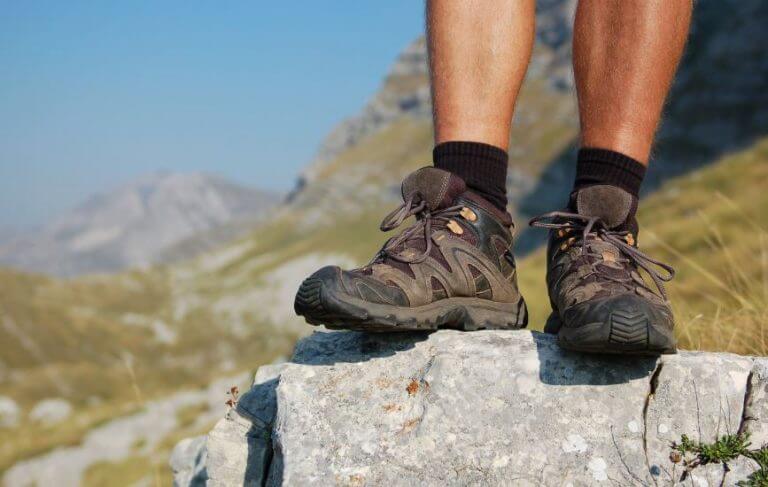 Um homem com botas para trekking em cima de uma pedra