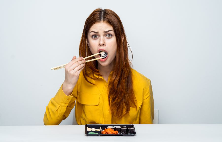 Menina comendo sushi com uma expressão de surpresa