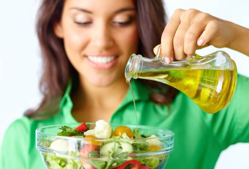 Mulher colocando azeite na salada
