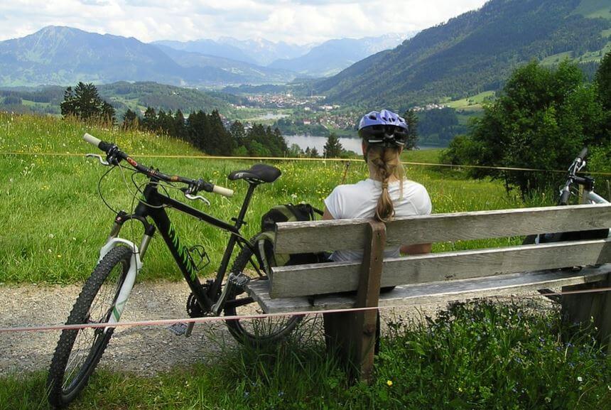 Mulher descansando com uma bicicleta nas montanhas