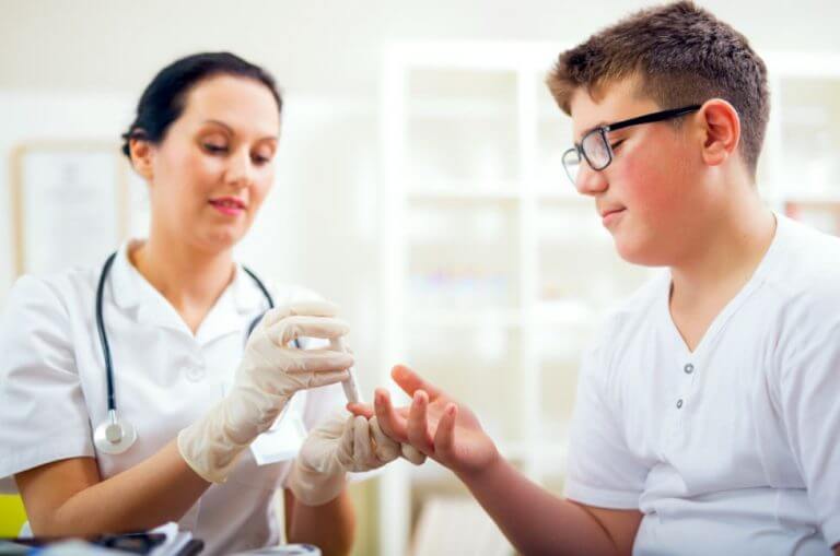 Médica medindo o nível de açúcar no sangue de um menino