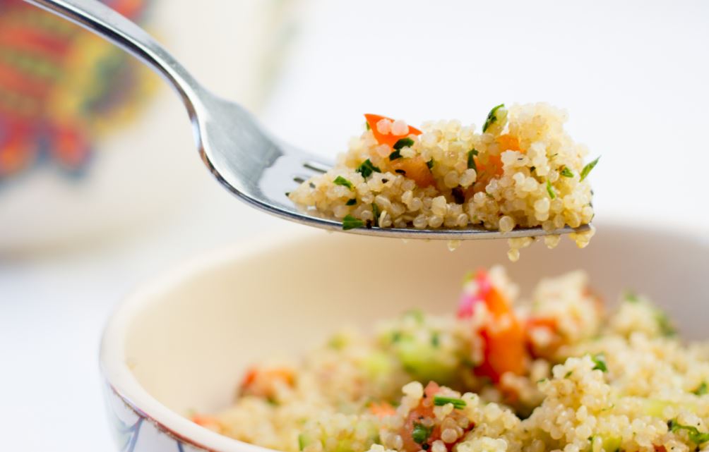 Um garfo com quinoa e um prato de salada