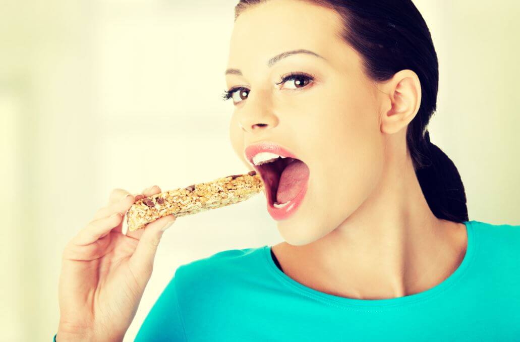 Mulher comendo barrinha de cereal