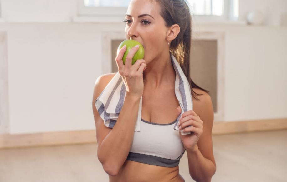 Mulher comendo uma maçã na academia