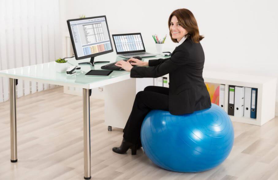 Mulher sentada em uma bola de Pilates no escritório