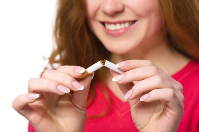 mulher quebrando um cigarro ao meio para parar de fumar