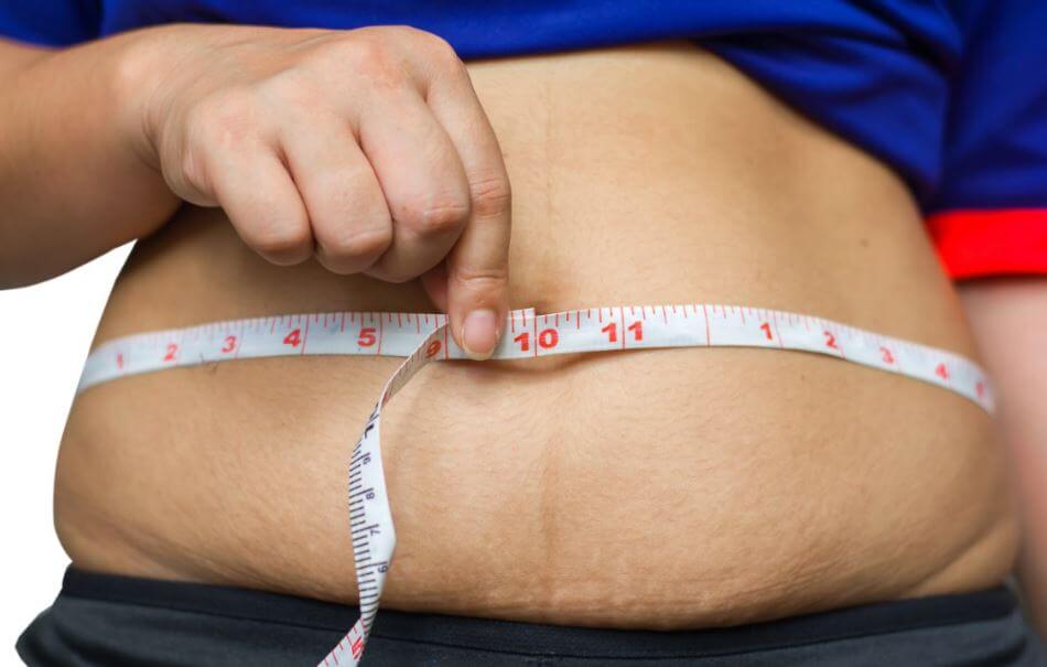 Pessoa medindo a barriga com uma fita métrica
