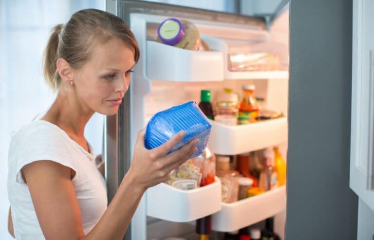 Mulher verificando alimento na geladeira