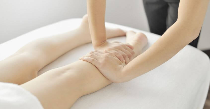 Uma mulher massageando as pernas de outra