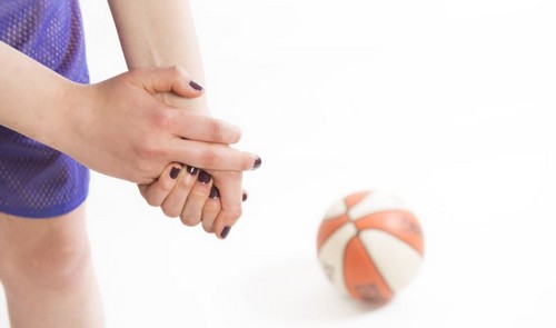 Menina com dor no dedo ao lado de uma bola de basquete