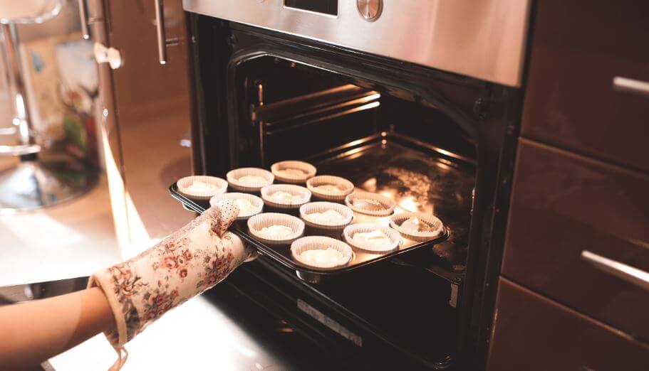 Moça colocando tortinhas no forno