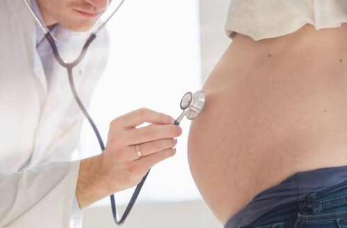 Médico escutando barriga de grávida