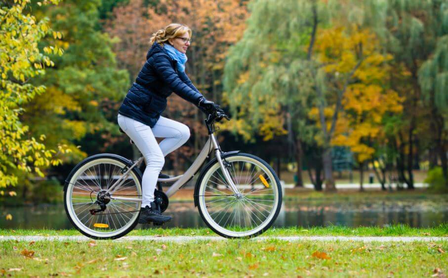 Mulher andado de bicicleta no outono e frio
