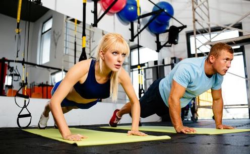 CrossFit egzersizinde şınav çeken kadın ve erkek.