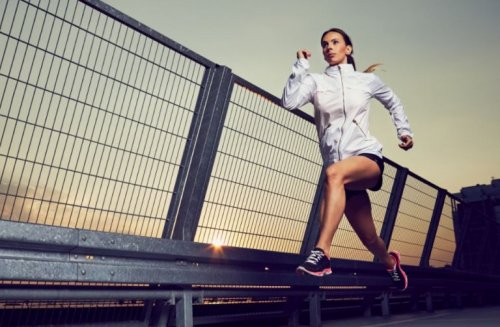Köprü üzerinden koşu yapan spor kıyafetli bir kadın.