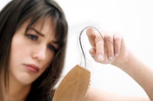 Dökülmüş saçlarını fırçadan temizleyen kadın.