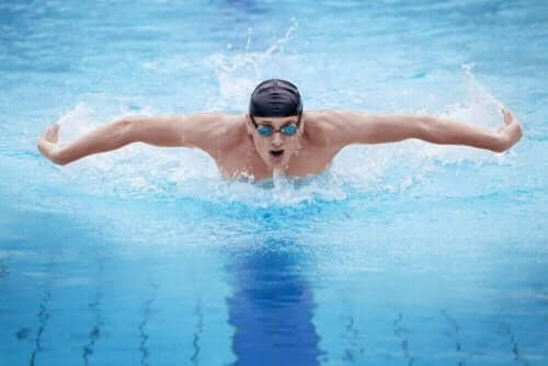 Bir adam havuzda kelebek stilinde yüzüyor