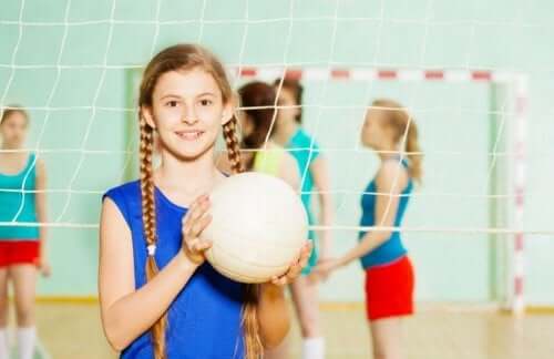 Elinde voleybol topu olan bir kız çocuğu.