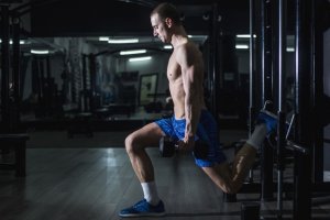 Man doing Bulgarian split squats with dumbbells.