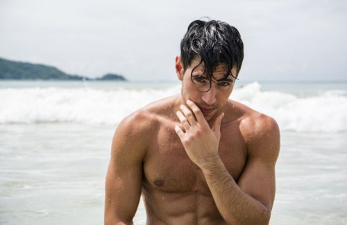 mandlig model på stranden med bølger i baggrunden