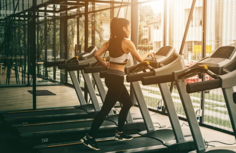 kvinde der løber på løbebånd alene i fitnesscenter
