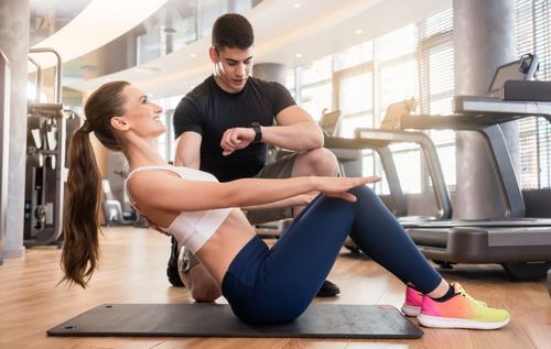 woman doing sit-ups properly at the gym with trainer